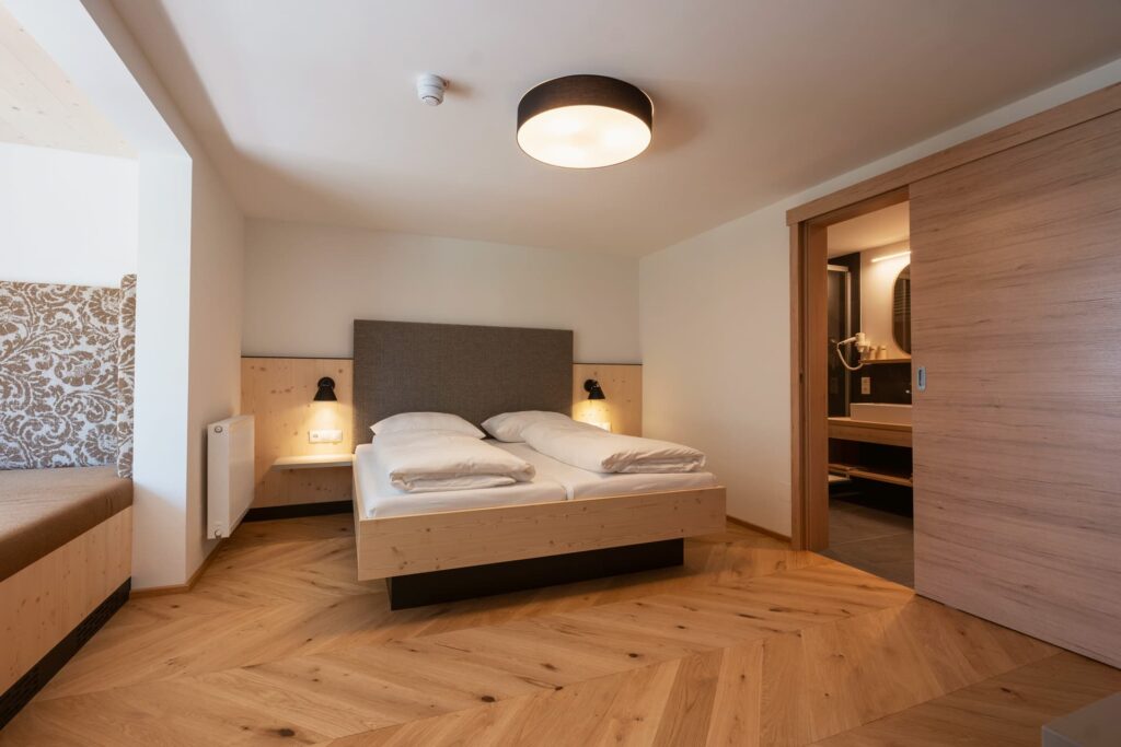 Bild vom Studio Lindenbaum im Schlafzimmer mit schönen Holzboden, Holzschiebetür und angenehmen warmen Licht